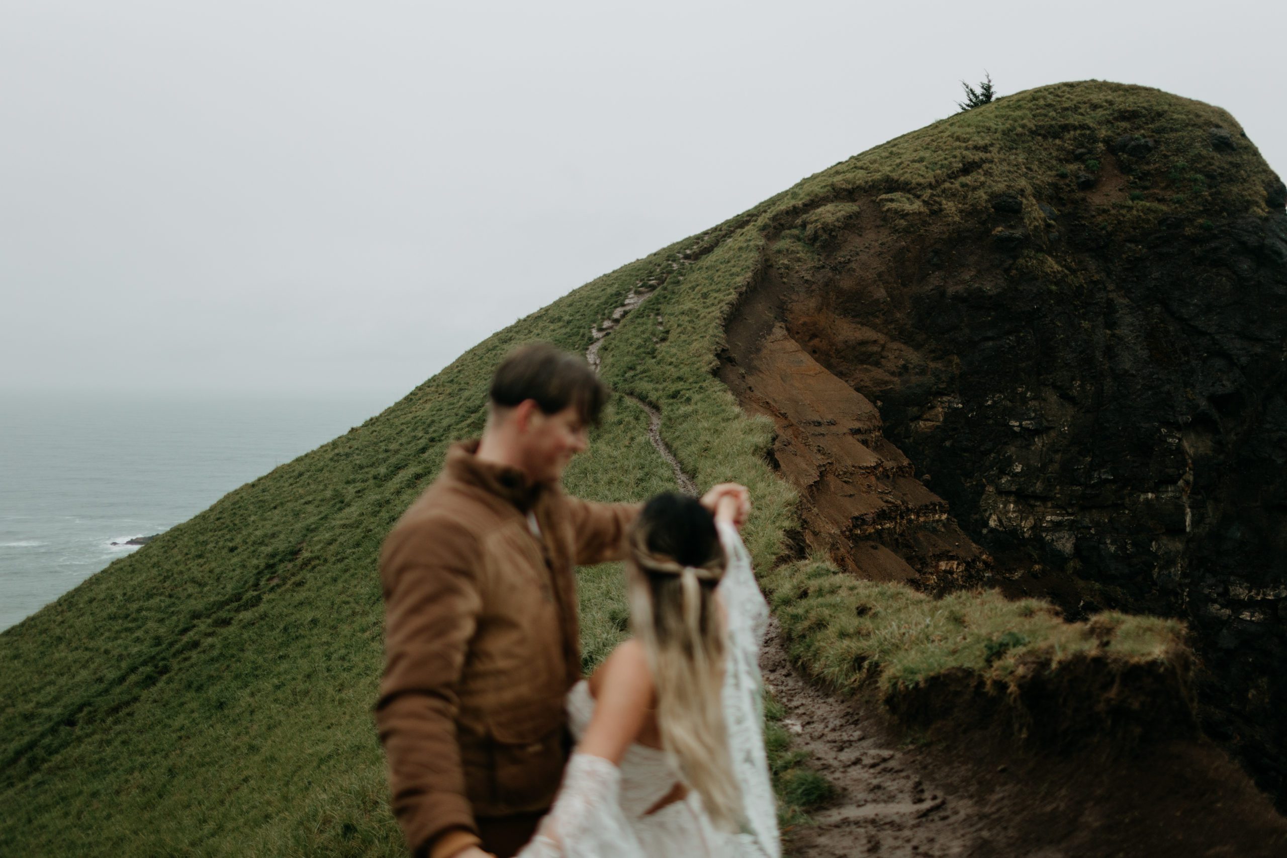 Bride and groom looking out towards coastal mountain in Oregon on a rainy day while holding hands