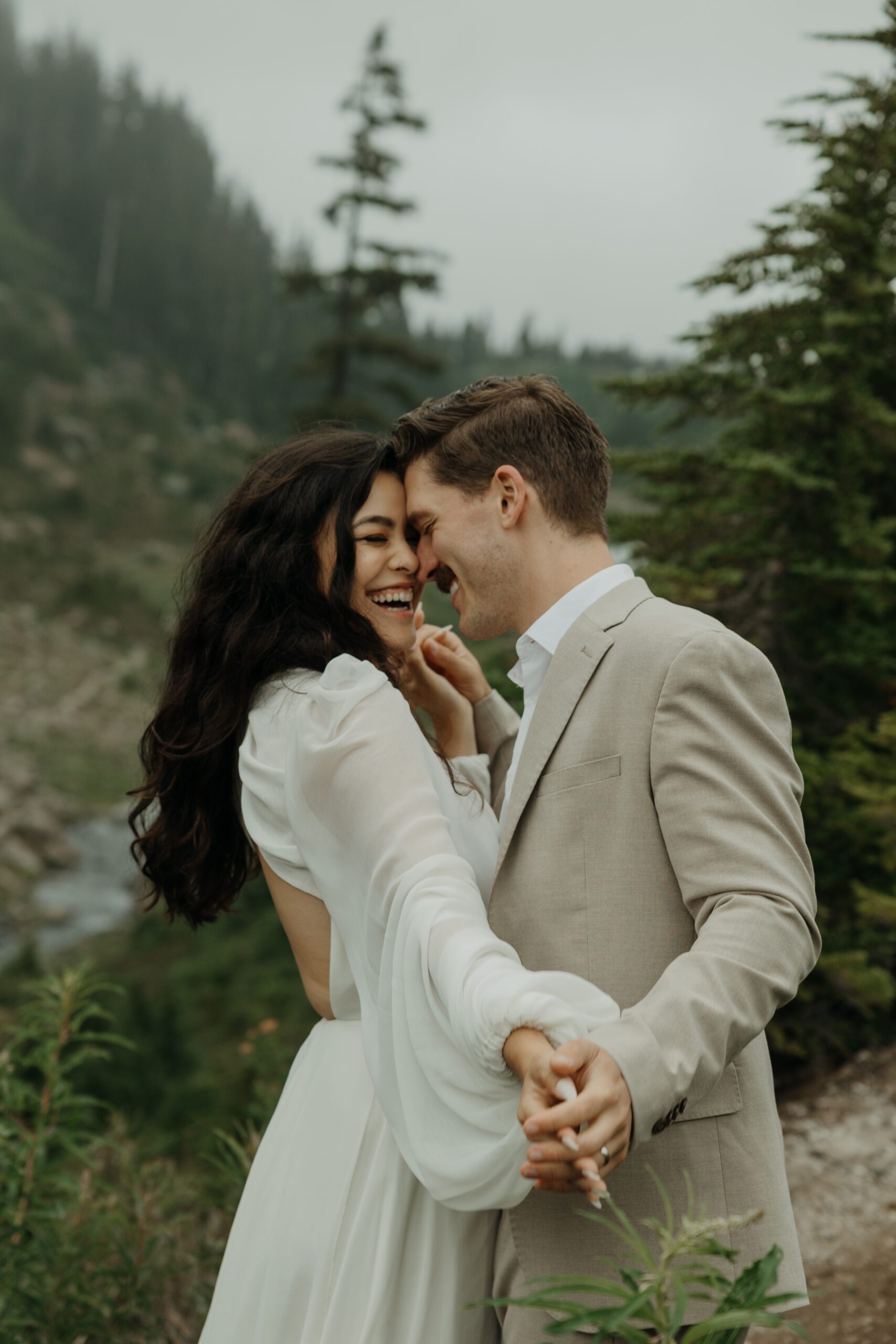 Elopement couple in neutral, white wedding attire smiling in North Cascades National Park, Washington