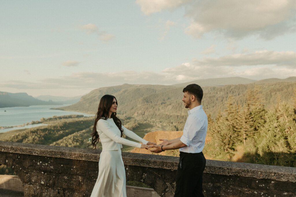 Engaged couple dancing with the view of the Columbia River Gorge from the Vista House behind them