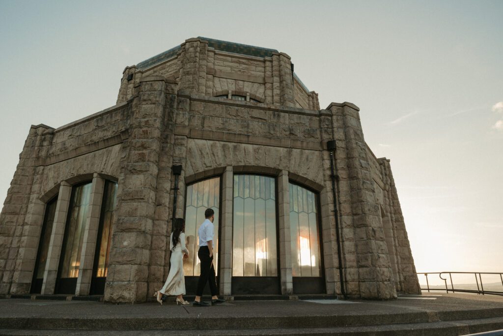 Candid and documentary golden hour engagement photos in the Columbia River Gorge, Oregon from the Vista House. Couple wears classic modern outfits