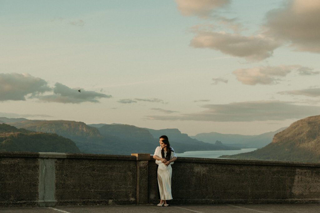 Engaged couple with the view of the Columbia River Gorge from the Vista House behind them