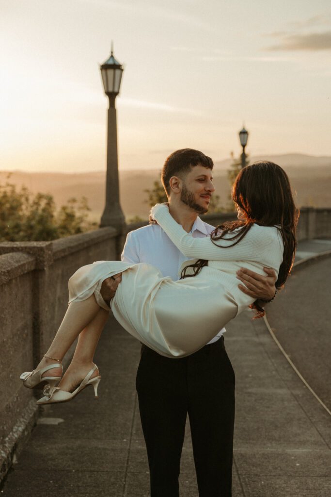 Engaged couple with the view of the Columbia River Gorge from the Vista House behind them